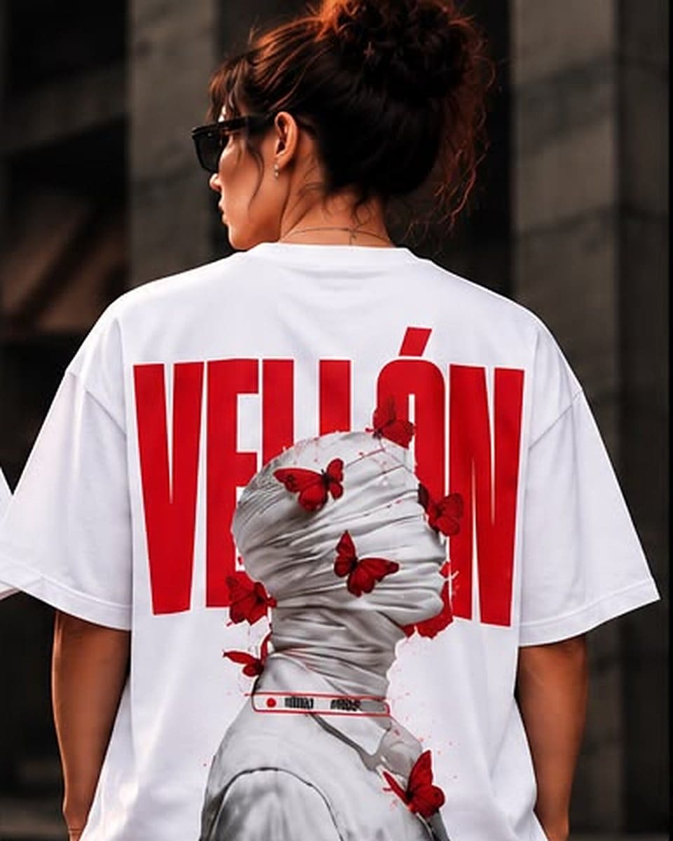 Camiseta oversize blanco, espalda: VELLÓN en letras rojas de bloque y una figura vendada rodeada de mariposas rojas